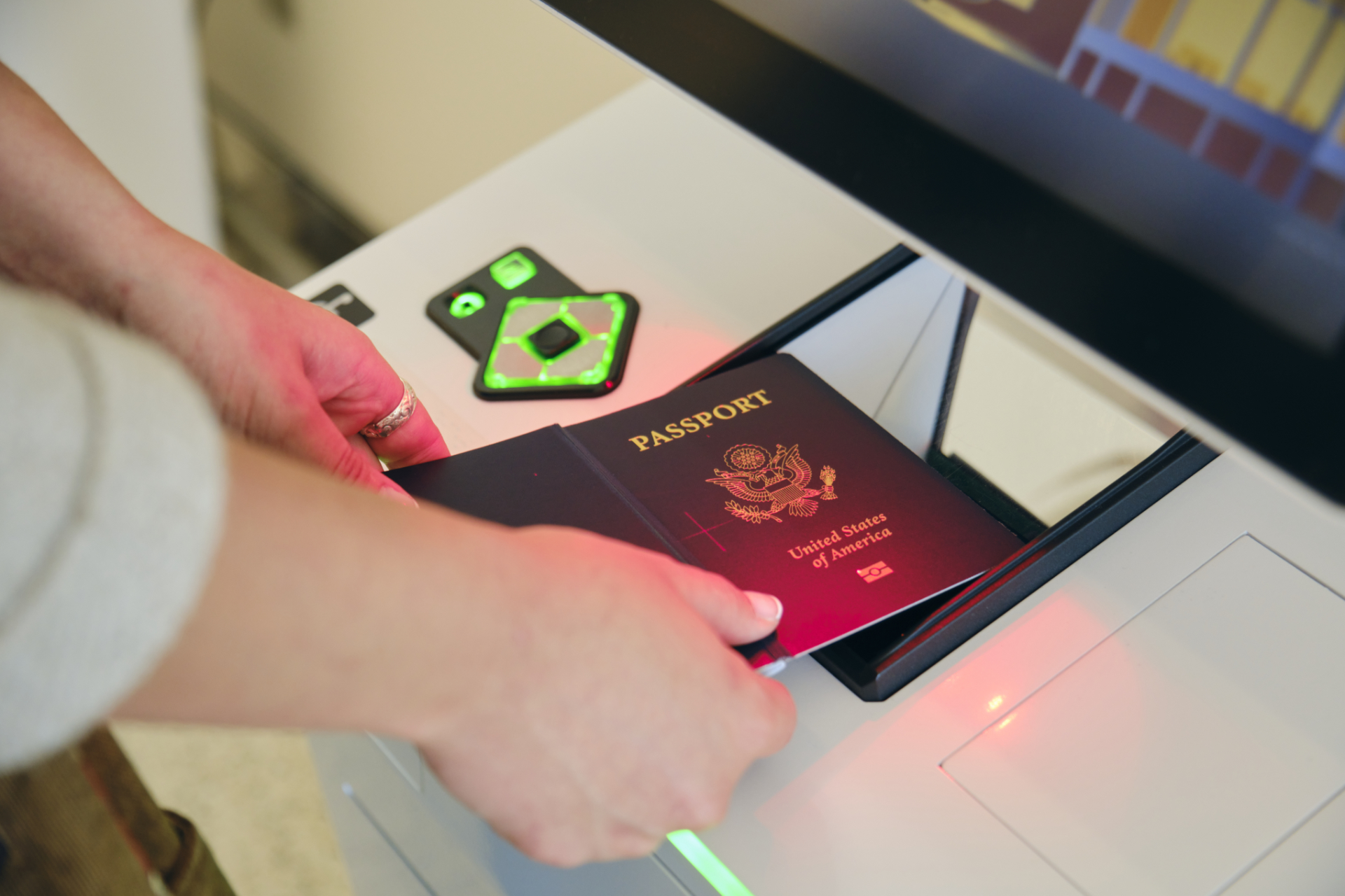 A person scans their passport at a check-in kiosk. The kiosk is equipped with a Storm Interface AudioNav keypad.