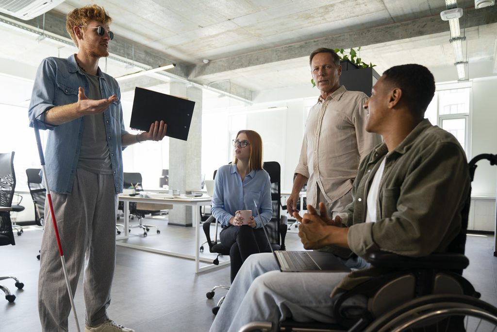 People in an office discussing accessibility with a visually impaired person.
